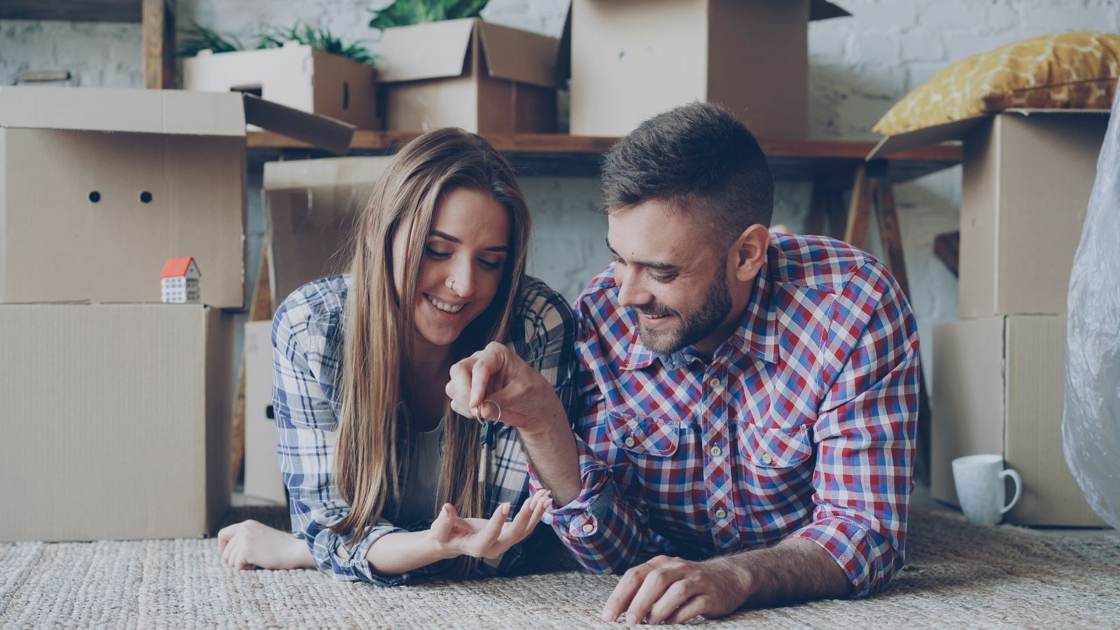 A joyful couple holding the keys to their new home among moving boxes
